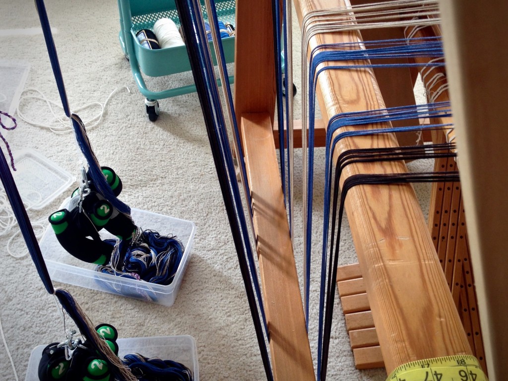 Beaming the warp under tension, using warping trapeze and weights.