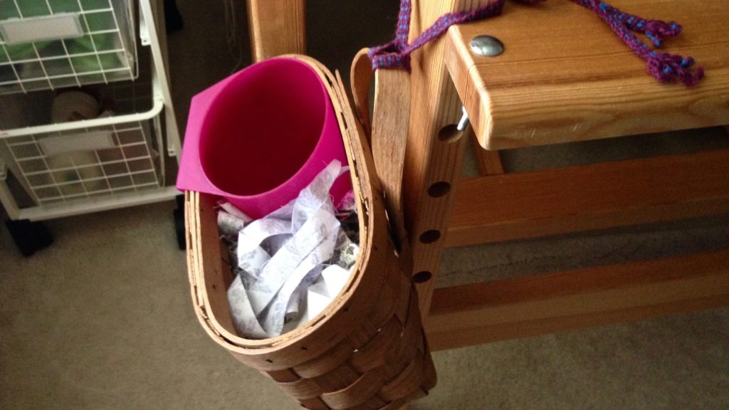 Loom basket is tied to the bench with an old inkle-woven band.